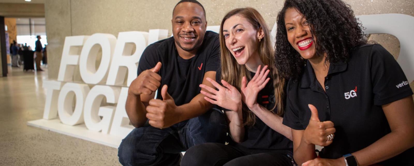 Verizon Employees Posing In Front Of A Forward Together Sign
