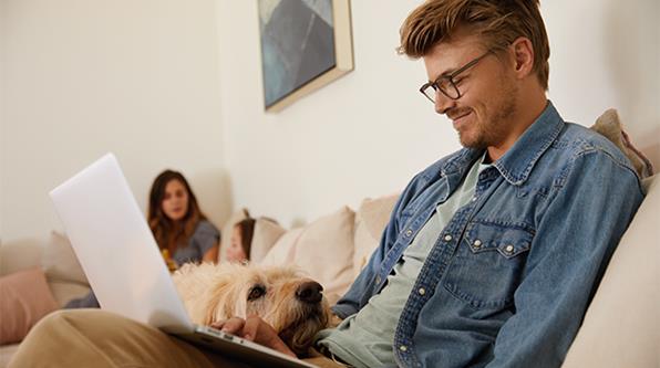 Man with dog and laptop on his lap