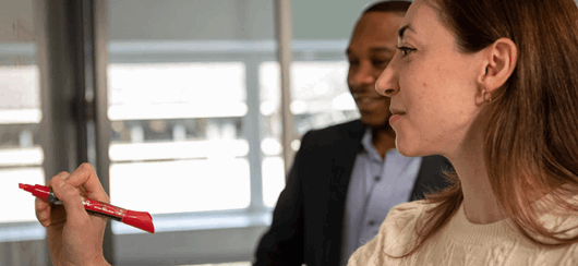 Woman And Man Working Together At A Whiteboard