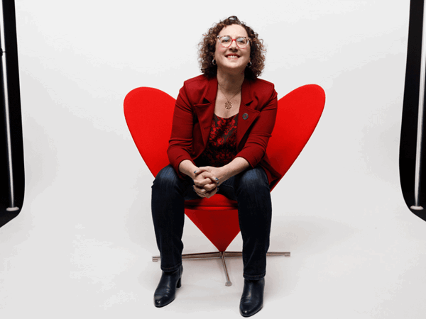 A Woman With Curly Hair Sitting On Red Chair In A Photo Studio