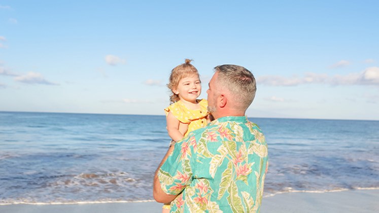 Mark holding his daughter on the beach